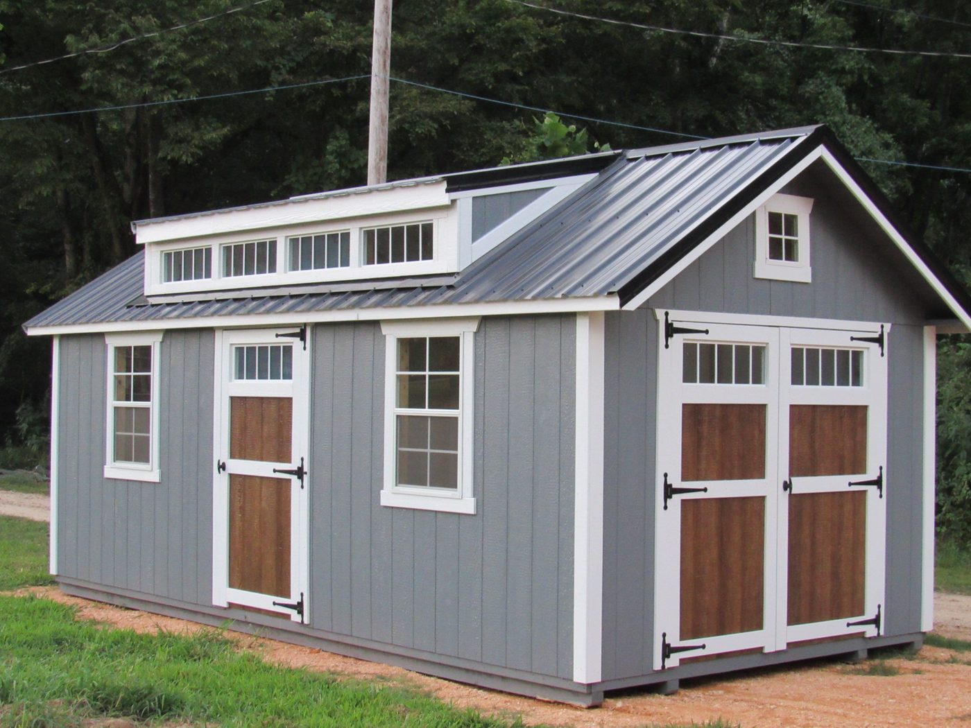 Gray Mission shed with transom dormer and wood-stained doors